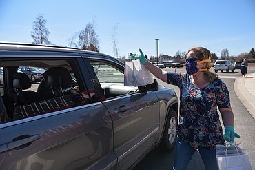 Brittany Trodick, K-3rd Grade Gathering Director at Canvas Church in Kalispell, hands out bags of Easter eggs and goodies to families in the parking lot of the church on Thursday. Canvas Church gave out over 1,000 bags containing around 22,000 eggs for the Easter holiday. (Casey Kreider/Daily Inter Lake)