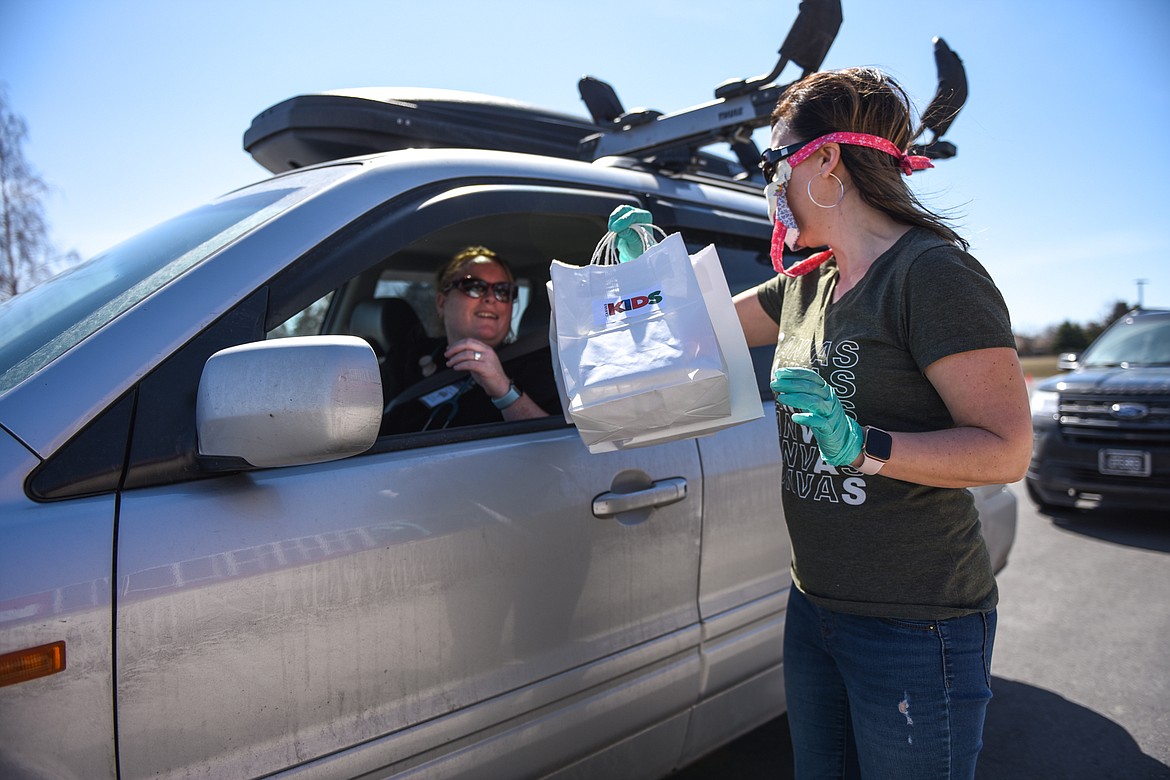 Lindsay Hecock, Kids Pastor at Canvas Church in Kalispell, hands out bags of Easter eggs and goodies to families in the parking lot of the church on Thursday. Canvas Church gave out over 1,000 bags containing around 22,000 eggs for the Easter holiday. (Casey Kreider/Daily Inter Lake)