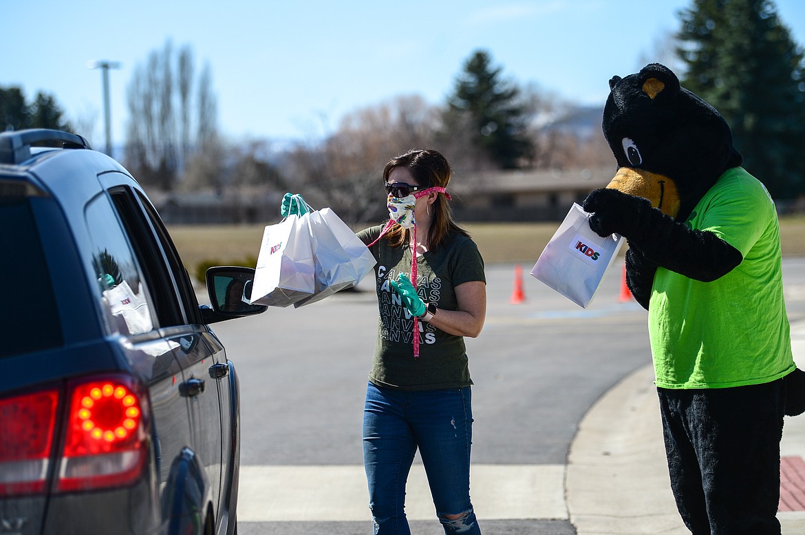 Cubbie the Bear gets a closer look at the contents of a bag as Lindsay Hecock, Kids Pastor at Canvas Church in Kalispell, hands out bags of Easter eggs and goodies to families in the parking lot of the church on Thursday. Canvas Church gave out over 1,000 bags containing around 22,000 eggs for the Easter holiday. (Casey Kreider/Daily Inter Lake) and Lindsay Hecock, Kids Pastor at Canvas Church in Kalispell, hand out bags of Easter eggs and goodies to families in the parking lot of the church on Thursday. Canvas Church gave out over 1,000 bags containing around 22,000 eggs for the Easter holiday. (Casey Kreider/Daily Inter Lake)