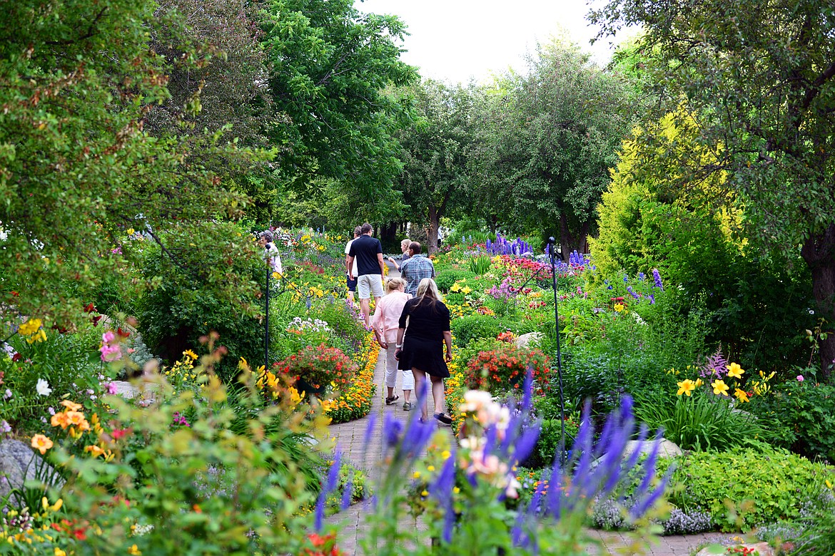 Visitors walk along a garden path full of blooming flowers during a Splendid Summer Evenings self-guided visit at Bibler Home and Gardens in Kalispell on Wednesday, July 22. Possible dates for future self-guided visits include their Sweet Summer Days on Aug. 3-4, though all tickets must be purchased in advance. (Casey Kreider/Daily Inter Lake)