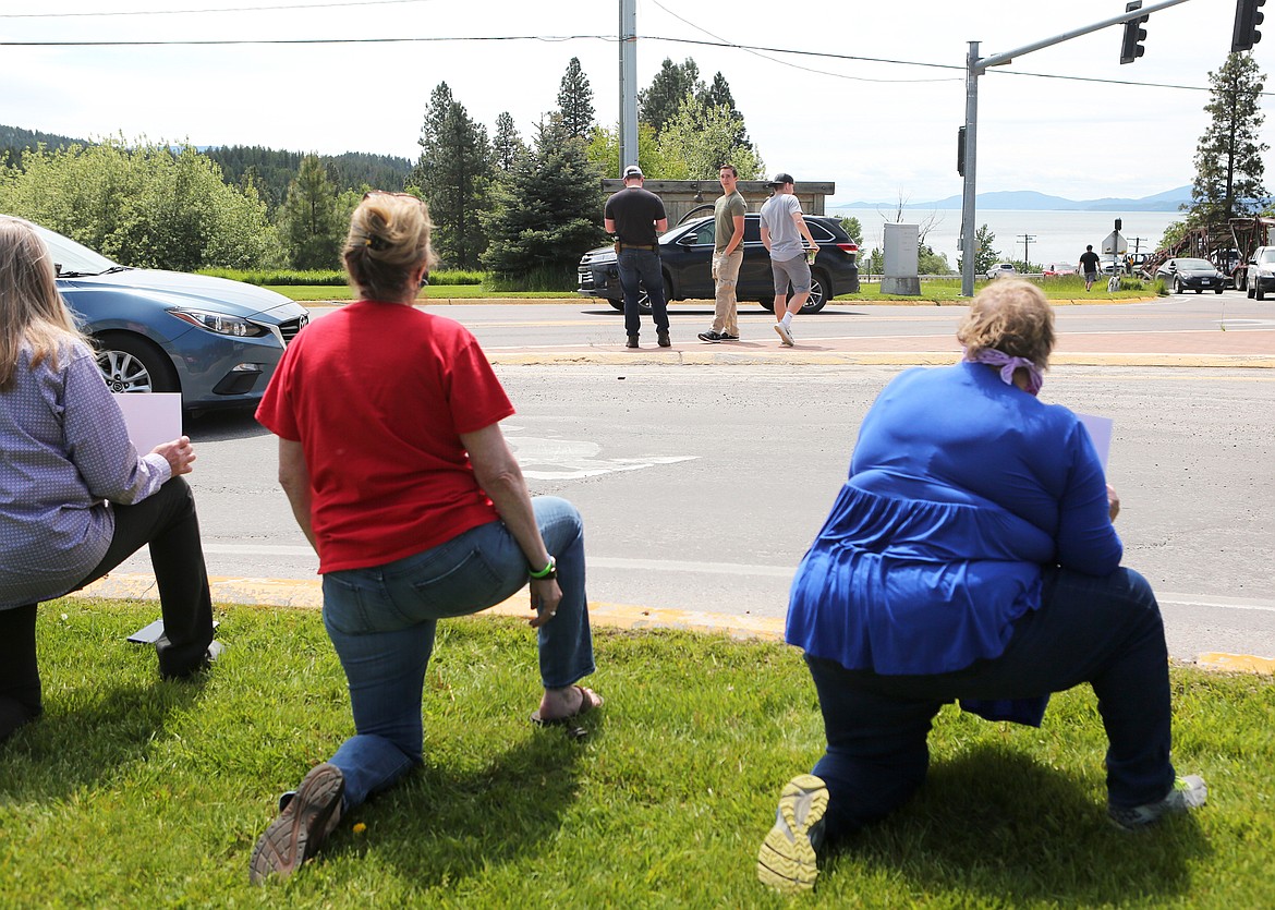 Three young men observe a group of demonstrators at the intersection of Holt Drive and Montana 35. The men said they came out to make sure the event stayed peaceful, but some demonstrators felt they were there to intimidate them.