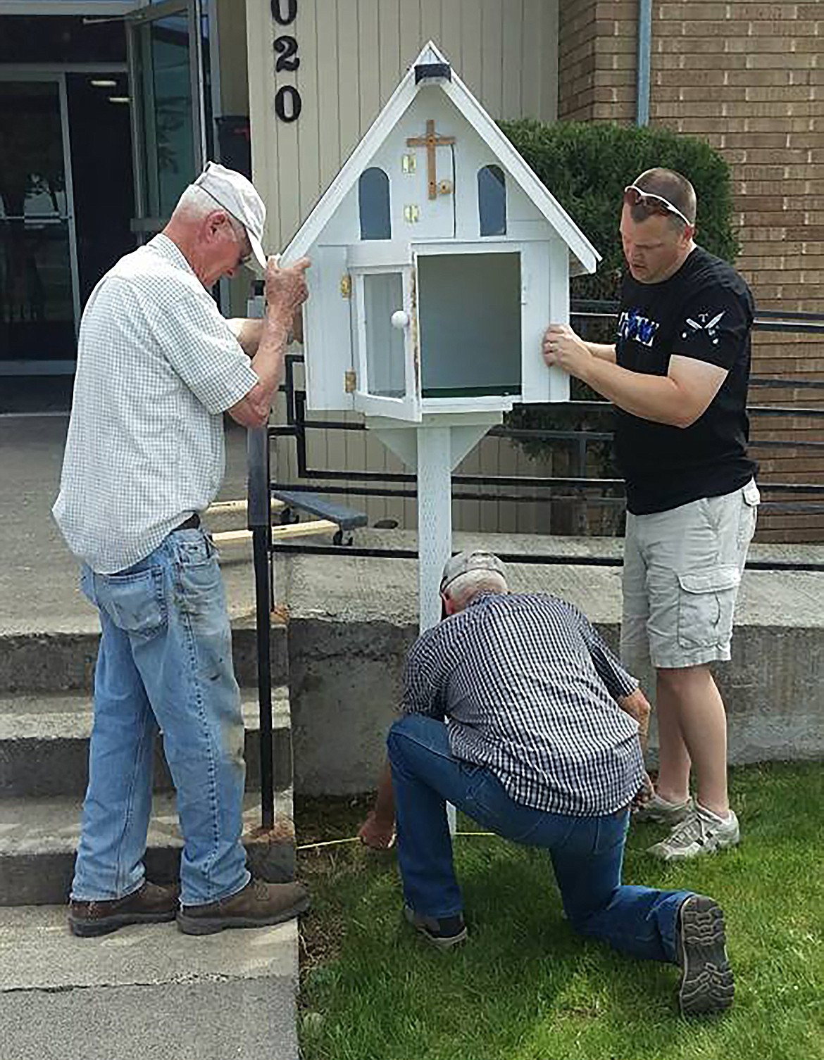 From left: Mel Martin, Lee Hall, and Kyle Cox prepare to install the concrete base for the Little Free Library in 2016.