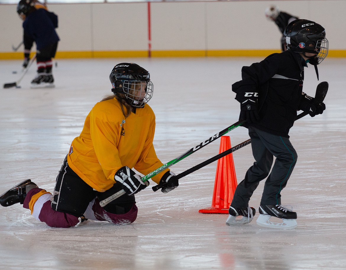 A young woman comes sliding around the cone on the rink as she’s pulled by a pair of hockey sticks at the Moses Lake Ice Rink on Monday morning at the Play Hockey Like a Girl event.