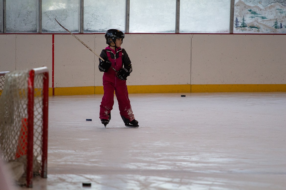 Stick held high, a young skater watches the commotion on the ice  on Monday morning as women and girls of a wide age range came out to participate in the Play Hockey Like a Girl event, sponsored by the Moses Lake Adult Hockey Association.