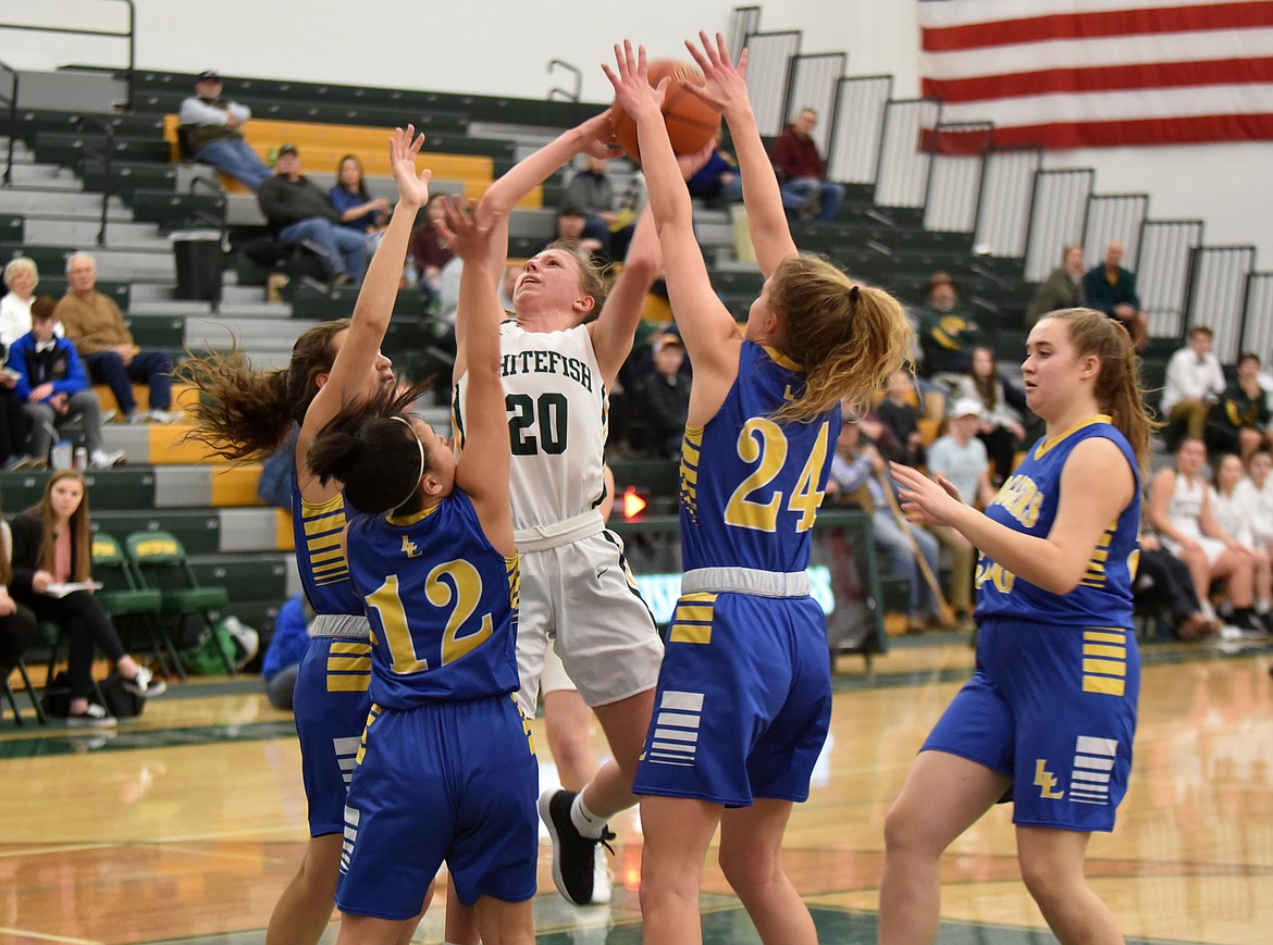 Surrounded by Logger defenders, Bulldog Mikenna Ells fights for the shot Friday night at the Whitefish High School gym. (Heidi Desch/Whitefish Pilot)