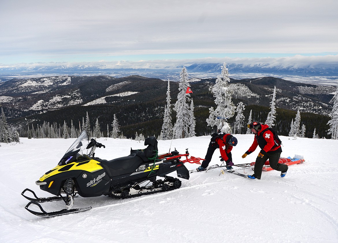 Colyne Hislop and Camas Garnett demonstrate attaching a rescue toboggan to the back of a snowmobile for a potential rescue.