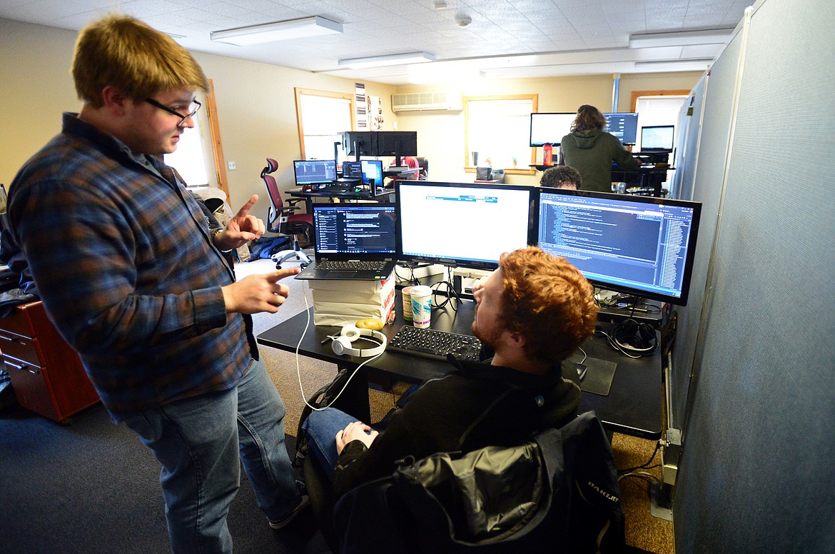 Developers Nathan Starkel, left, and Jayson Potter converse at Potter’s workstation at WaterStreet in Kalispell on Wednesday, Feb. 12. (Casey Kreider photos/Daily Inter Lake)