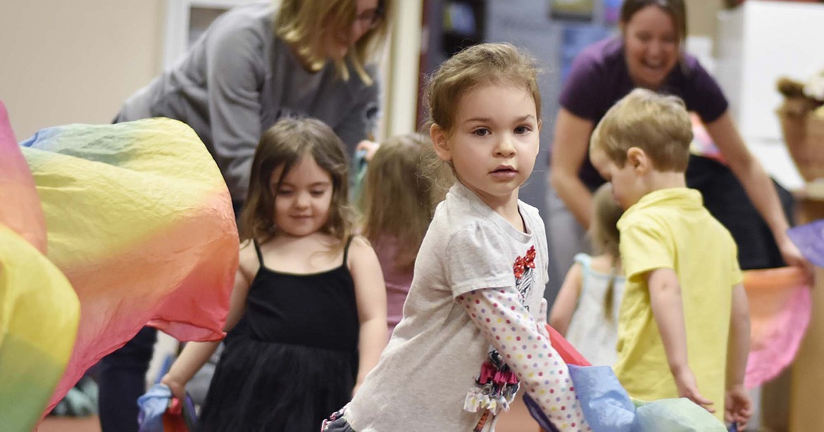 Vivian Ostrem, 4, plays waves around a piece of colorful fabric while dancing to music  during North Valley Music School’s Music Together class at The Springs at Whitefish on Wednesday afternoon. (Heidi Desch/Whitefish Pilot)