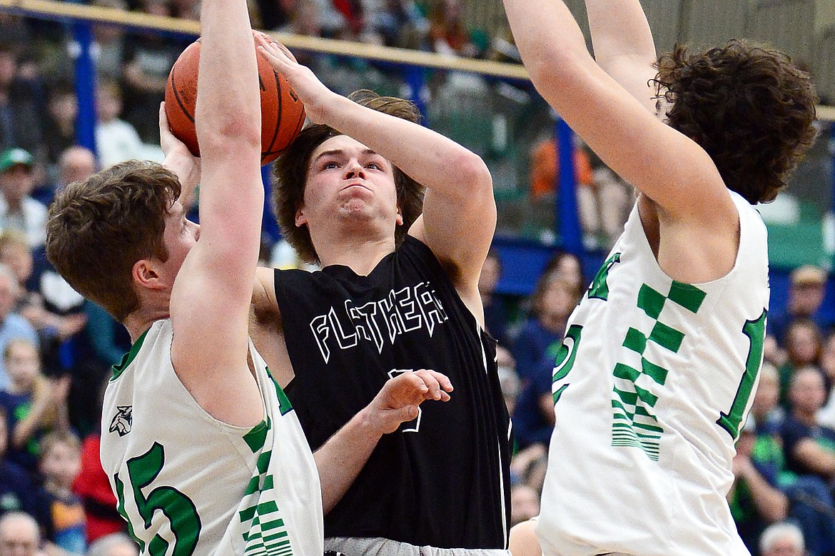 Flathead's Tannen Beyl (5) drives to the basket between Glacier's Drew Engellant (15) and Weston Price (12) during a crosstown matchup at Glacier High School on Friday. (Casey Kreider/Daily Inter Lake)