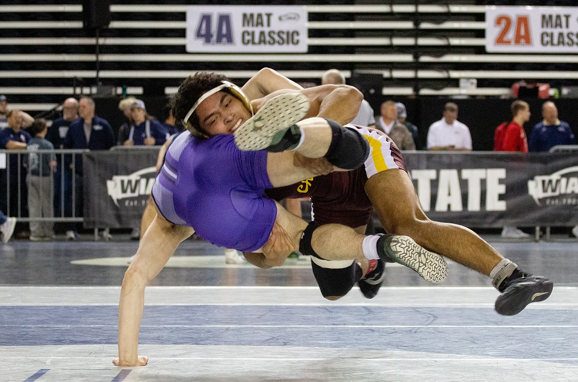 Casey McCarthy/Columbia Basin Herald Moses Lake's Cruz Vasquez hangs midair before taking his opponent to the mat in the third-place bout on Saturday at the  Mat Classic XXXII.