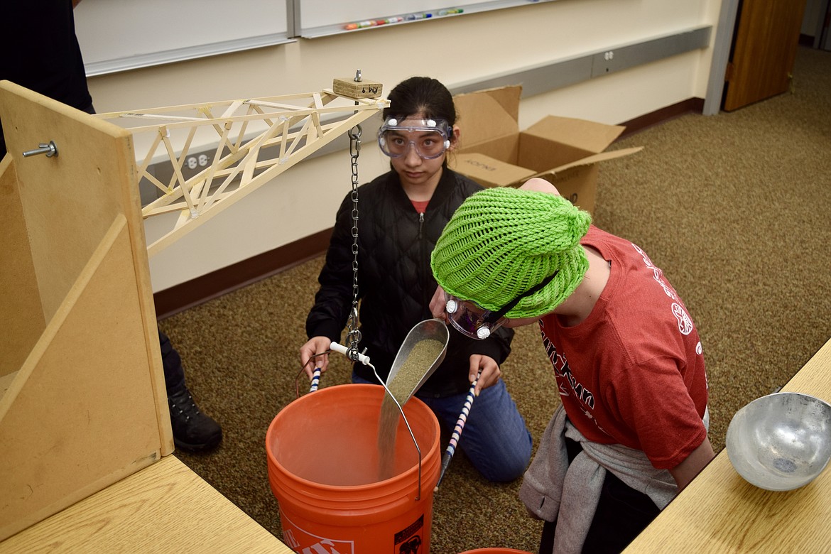 Charles H. Featherstone/Columbia Basin Herald
Anita Valdez and Libby Retterer, both eighth graders from St. Joseph’s Catholic School in Kennewick, fill up a buck with sand to test the ability of the “boomilever” they built to bear weight as part of the middle school Science Olympiad at Big Cend Community College on Saturday.