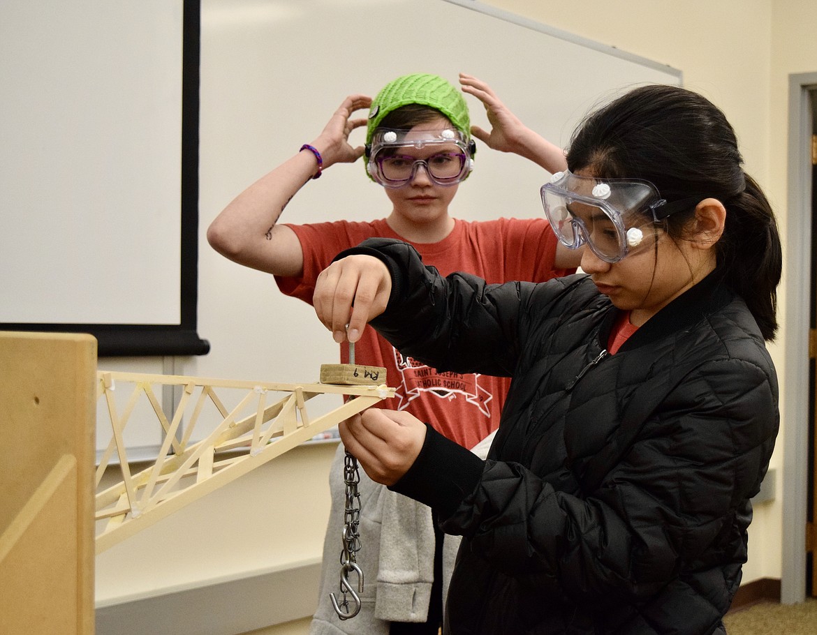 Anita Valdez and Libby Retterer, both eighth-graders from St. Joseph’s Catholic School in Kennewick, get ready to test the ability of the “boomilever” they built to bear weight as part of the middle school Science Olympiad at Big Bend Community College on Saturday.