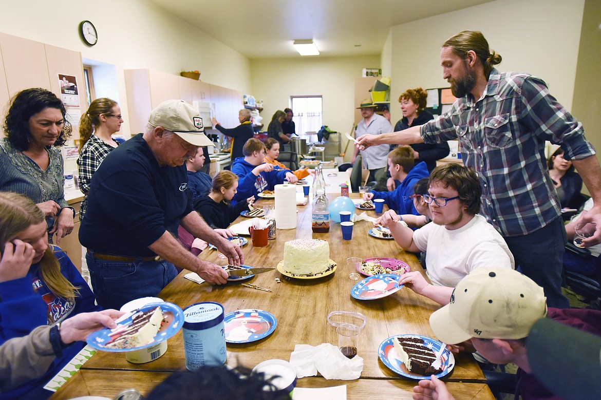 Volunteer Tony Budesa, standing left, and paraeducator Jon Blankenship, standing right, hand out slices of chocolate layer cake and silverware to Columbia Falls students during their “Able Table” program at North Valley Food Bank on Tuesday, March 11. Casey Kreider/Daily Inter Lake)