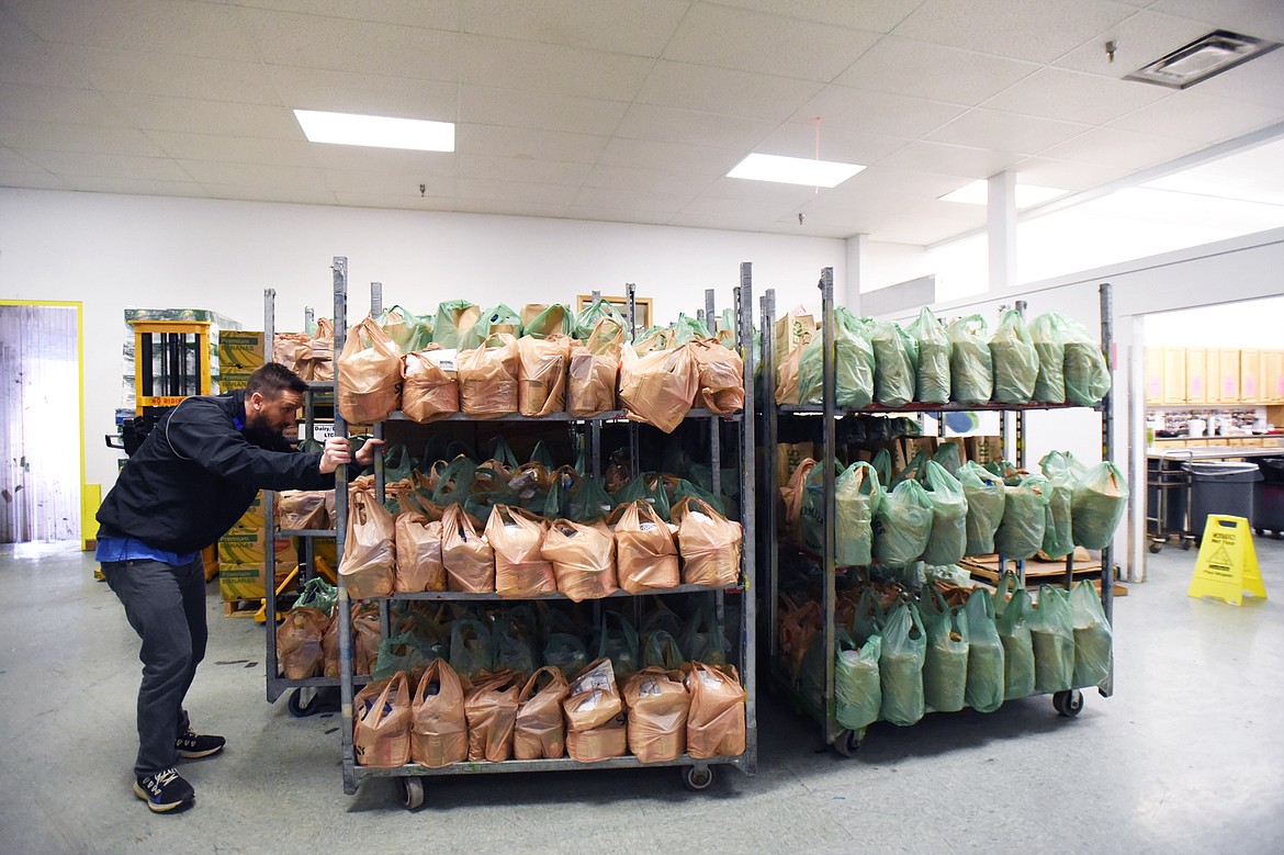 Ryan Nollan, with Fresh Life Church, arranges carts full of bagged meals at the Flathead Food Bank on Tuesday, March 17. (Casey Kreider/Daily Inter Lake)