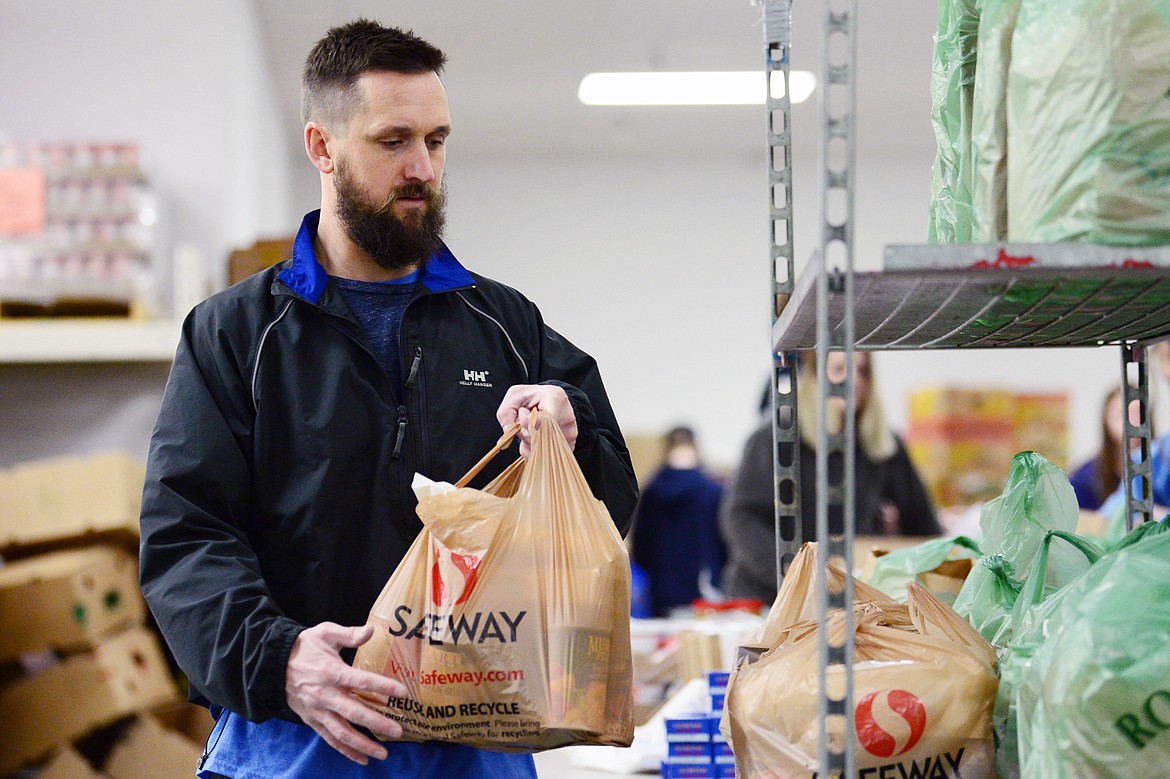Ryan Nollan, with Fresh Life Church, organizes bagged meals on carts for distribution at the Flathead Food Bank on Tuesday, March 17. (Casey Kreider/Daily Inter Lake)