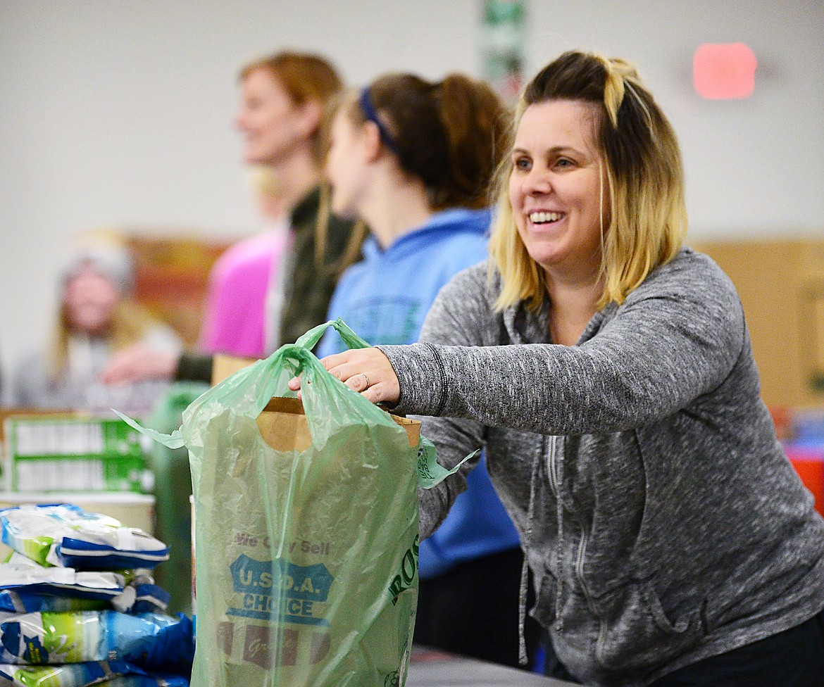 Michelle Nollan, with Fresh Life Church, puts meals into bags for distribution at the Flathead Food Bank on Tuesday, March 17. (Casey Kreider/Daily Inter Lake)