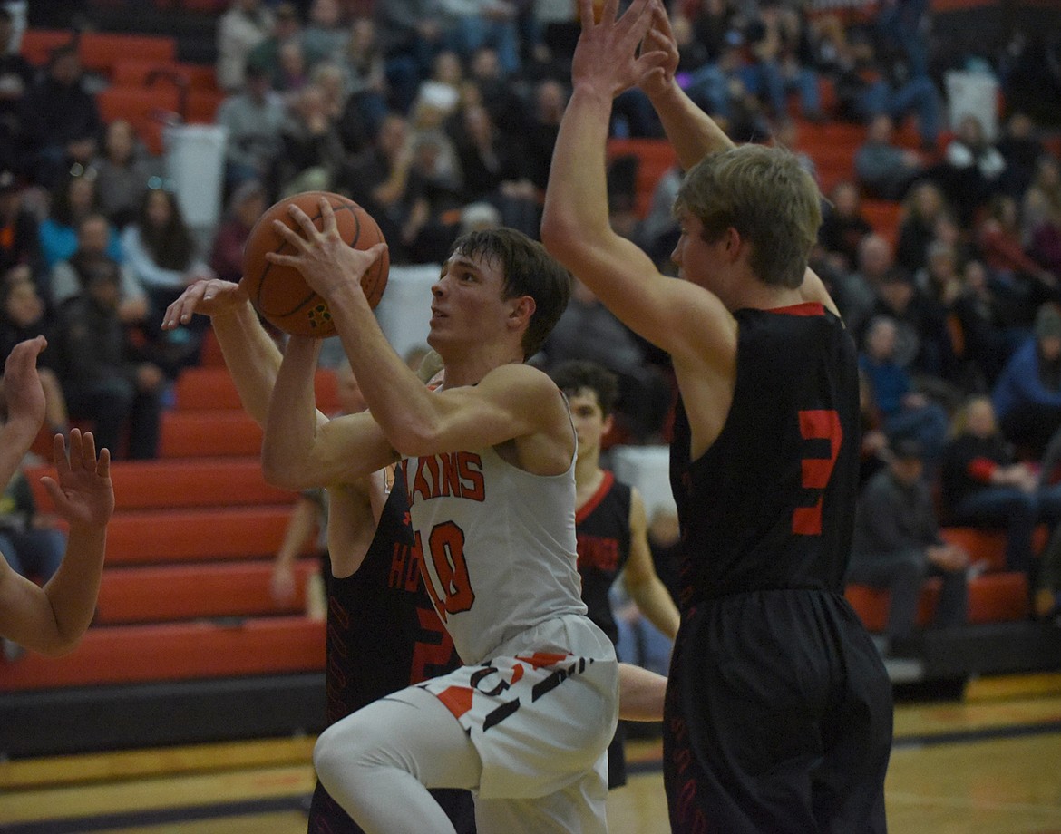 Plains guard Treydon Brouillette gets between Hot Springs defenders Lincoln Slonaker (2), Jack McAllister (3) and Brandon Knudsen (20) for a shot attempt during the 14-C District tournament in Ronan.  (Scott Shindledecker/Valley Press)