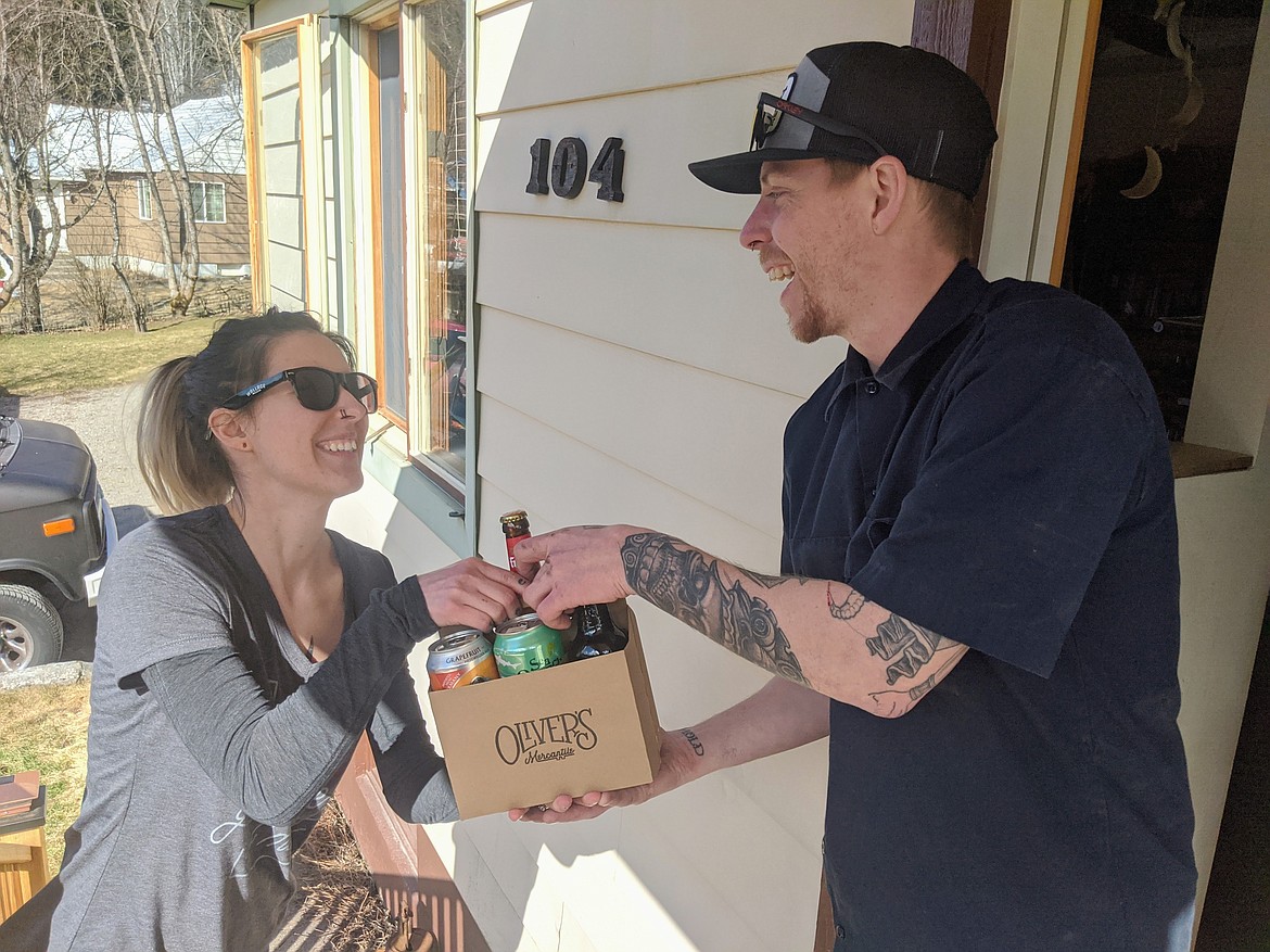 Photo by CHANSE WATSON/
Oliver’s Mercantile employee Alannah Ford makes a beer delivery to Michael Hutchins in Silverton on Friday. Oliver’s is accepting delivery orders during normal business hours.