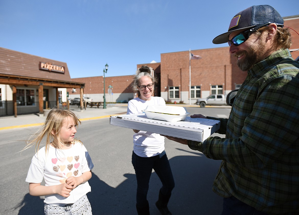 Chris Brooks, right, and his daughter Bella pick up a takeout order from Becky Ojennes at Jersey Boys Pizzeria in Whitefish on March 19. On Thursday, the Flathead City-County Health Board voted to close all bars, restaurants, casinos and fitness facilities to the public for at least 10 days in an effort to fight the coronavirus pandemic, but many restaurants have converted to curbside pickup service. (Casey Kreider/Daily Inter Lake)