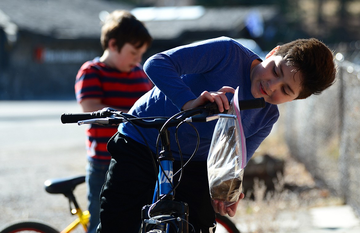 Youngsters hang bags of grab-and-go meals from their bike handlebars outside Bigfork ACES on Wednesday, March 18.