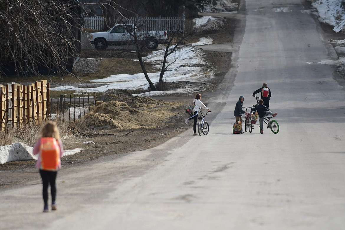 Students walk home with the day's lunch, tomorrow's breakfast and a week's worth of spring break groceries in Martin City on Thursday, March 19. (Teresa Byrd/Hungry Horse News)