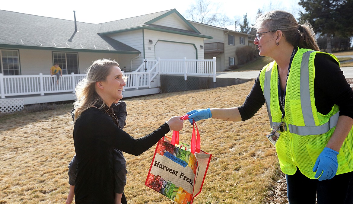 $ID/NormalParagraphStyle:MACKENZIE REISS PHOTOS | Bigfork Eagle
$ID/NormalParagraphStyle:Paraprofessional and bus aide Juanita Wiley delivers a bag of school supplies to a parent in the Crestview Drive area last Thursday, March 18.