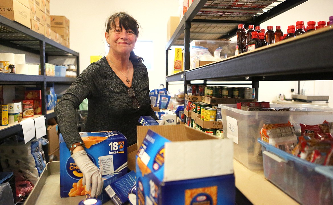 Kathleen Whitney, of Ferndale, unpacks boxes of mac ‘n’ cheese at the Bigfork Food Bank on Monday morning. (Mackenzie Reiss/Bigfork Eagle)