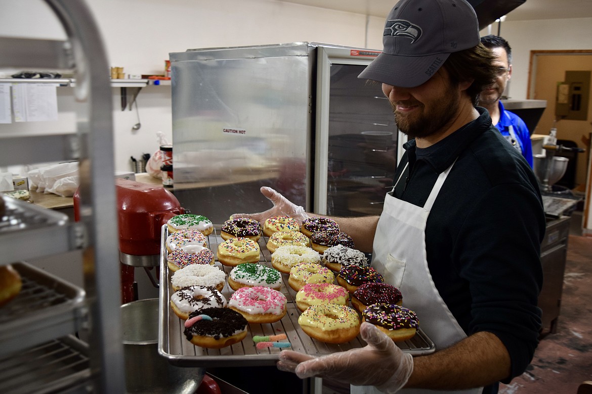 Troy Boorman carries a try of donuts he’d just decorated.