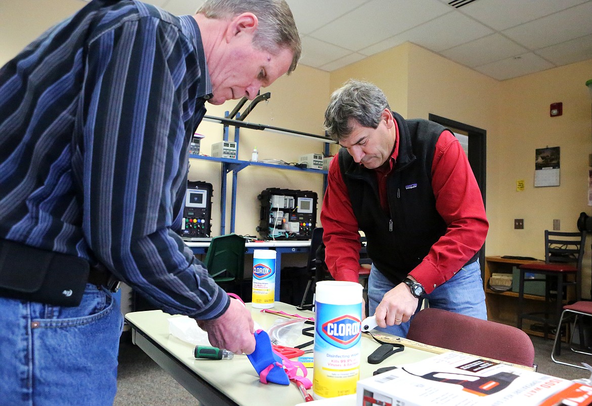 Don Skare, the facilities coordinator, and Peter Fusaro, the director of trades and industrial arts, tie elastic straps to the completed N95 masks. (Mackenzie Reiss/Daily Inter Lake)