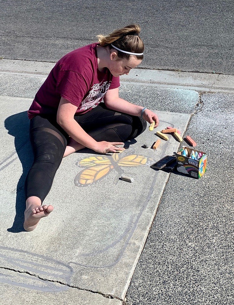 Ryan Hays, of Moses Lake, working on one of her driveway artworks, with chalk.