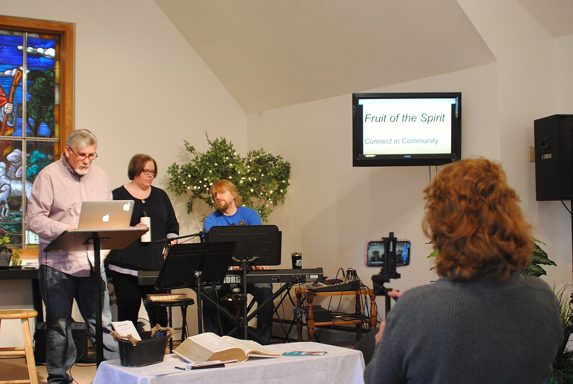 Barbara Morris makes final adjustments to the video screen on her iPhone while Derek and Shelly Larson warm up for online worshiping at New Day Fellowship in St. Regis last Sunday. (Amy Quinlivan/Mineral Independent)