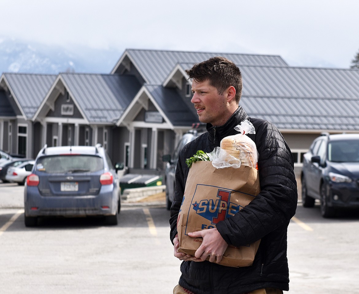 Volunteer Jaren Sousa caries a sack of food out to a car Thursday afternoon at North Valley Food Bank. (Heidi Desch/Whitefish Pilot)
