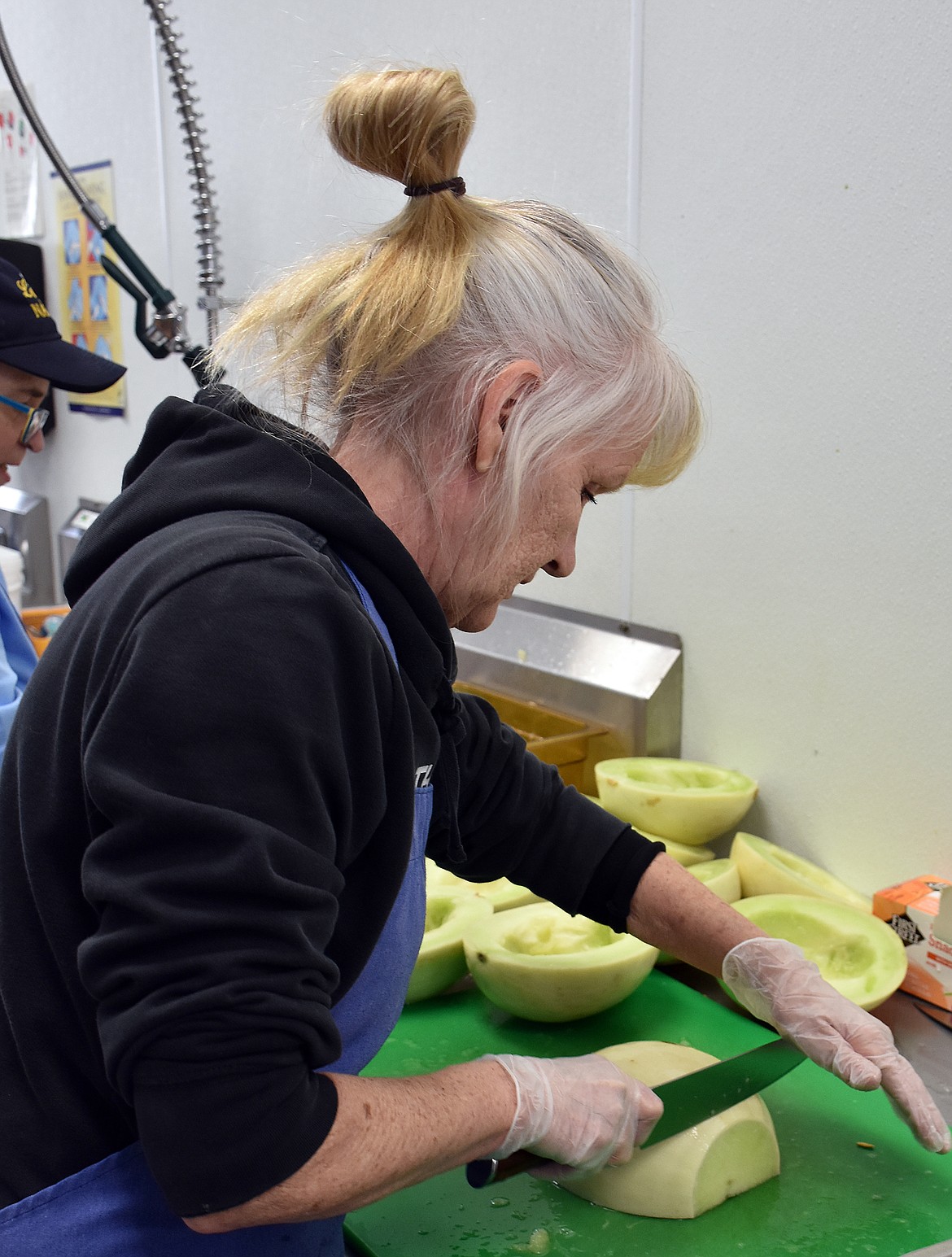 Becky Sarbaum of Libby Public Schools food services slices honeydew melons bound for students staying at home across the district. (Duncan Adams/The Western News)