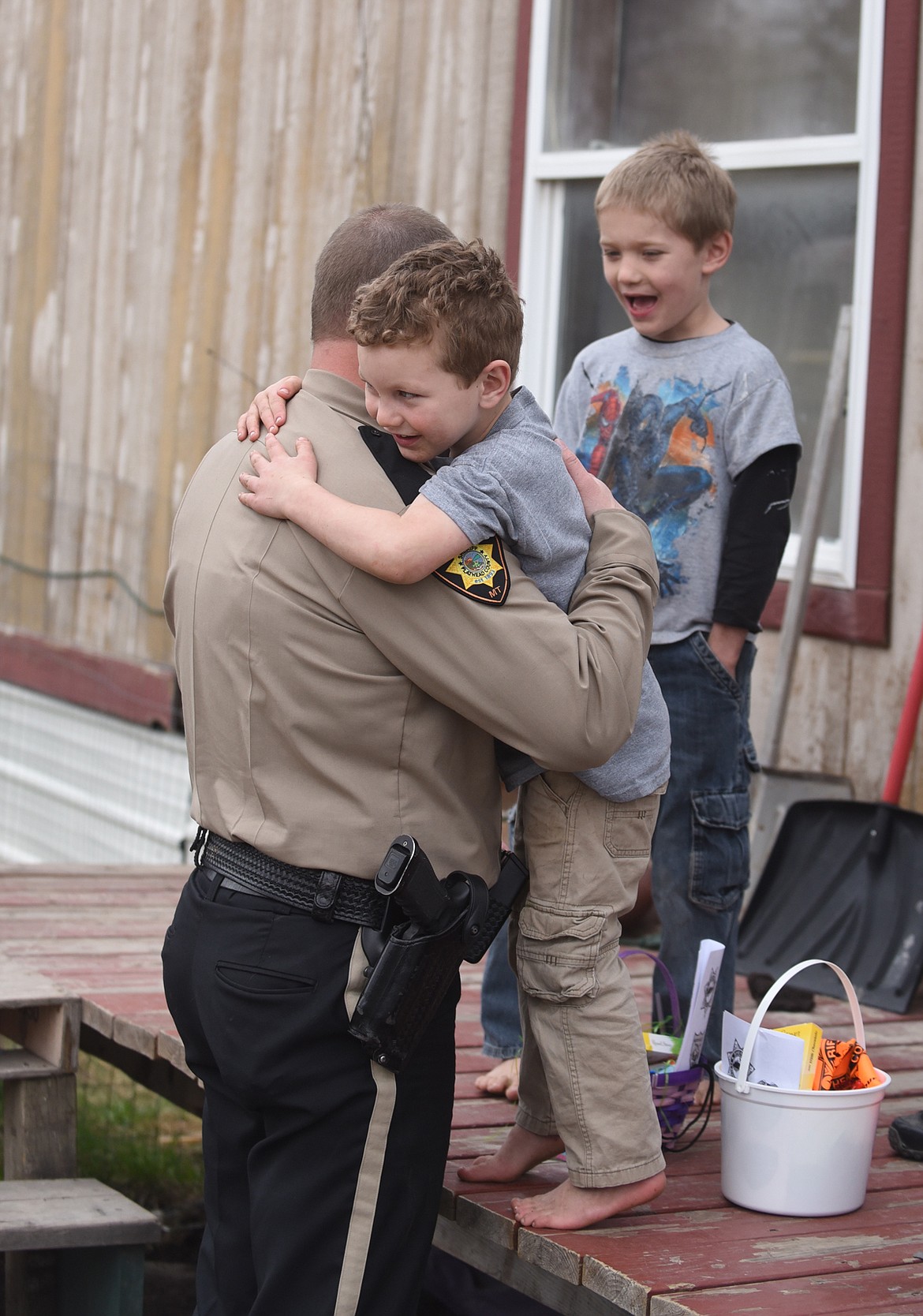 Flathead County Sheriff Brian Heino gets a hug from Elliott Rush after he delivered Easter baskets to Rush and Jacob Harper Friday. (Scott Shindledecker/Daily Inter Lake)