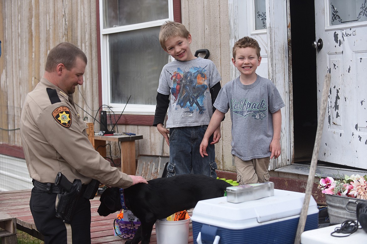 Jacob Harper, left, and Elliott Rush, celebrate Good Friday as Flathead County Sheriff Brian Heino delivers Easter baskets. Heino had the idea and law enforcement officers and others in the valley came together to donate baskets, candy and toys for 500 youth. (Scott Shindledecker/Daily Inter Lake)