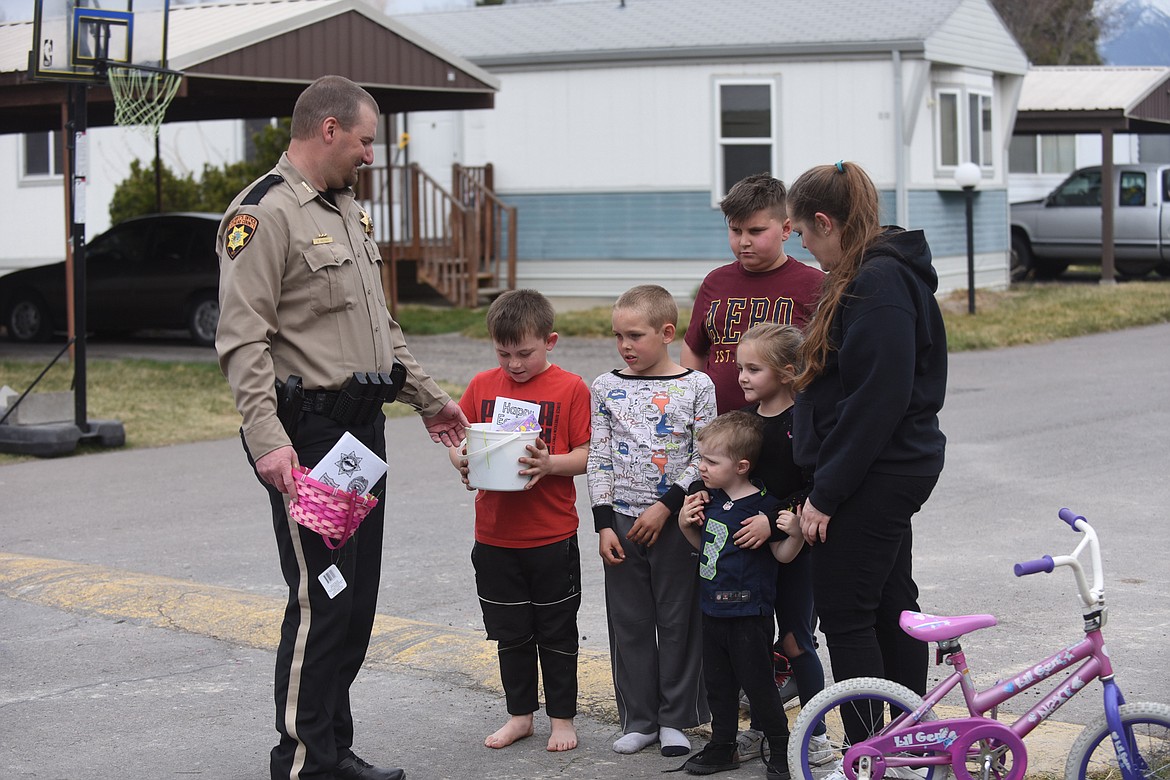 Flathead County Sheriff Brian Heino delivers a few of the 500 Easter baskets he and fellow law officers across the valley distributed to youths. From left, Heino, Jaxon Olsen, Bradley Hiebert, Logan Baltramais, Astryd Roberts, Everett Phillips and Jewel Hiebert. (Scott Shindledecker/Daily Inter Lake)