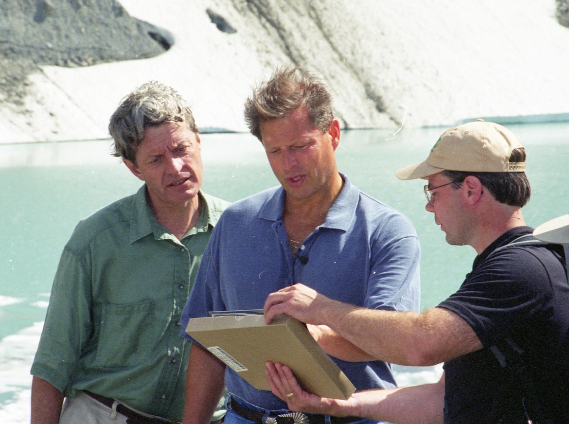 A young Dan Fagre shows former Vice President Al Gore, center, photos of Grinnell Glacier while former Sen. Max Baucus looks on in this photo from the summer of 1997. Gore hiked to Grinnell Glacier.