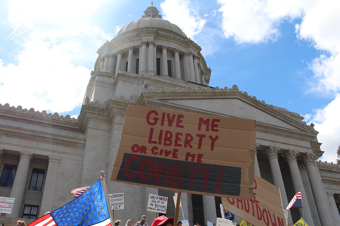 Cameron Sheppard/WNPA News Service 
 Protestors to Inslee’s “stay home, stay healthy,” order hold signs in front of the legislative building.