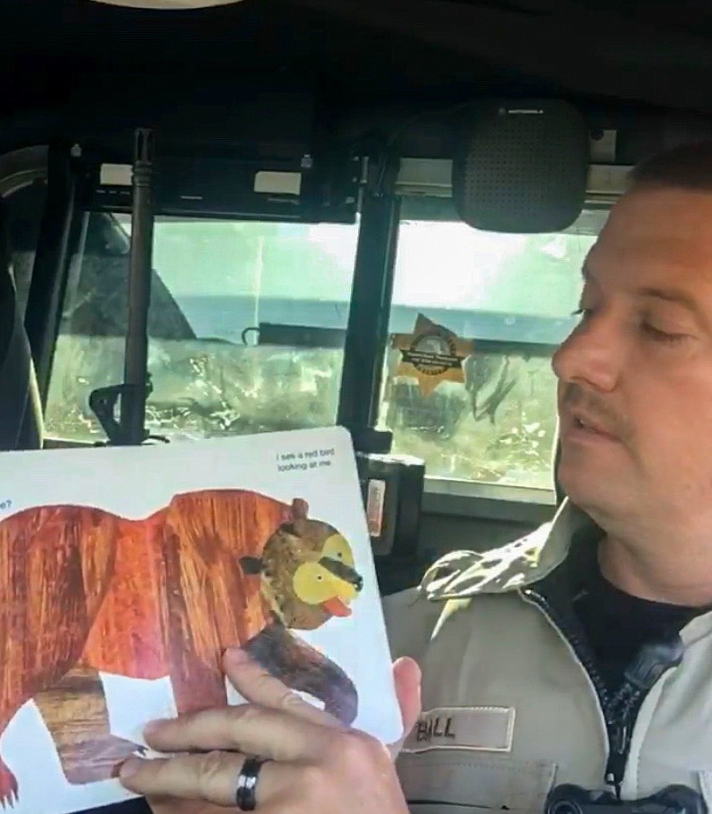 Corporal Jason Ball reads aloud to children from the confines of his patrol car as part of a new initiative by the Grant County Sheriff’s Department to connect with children in the community while they’re stuck at home.