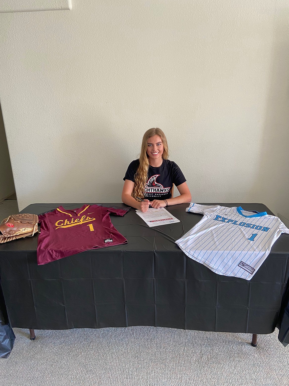 Courtesy Photo/Moses Lake senior, Gina Skinner, signs to play sotball next season at NNU with her Moses Lake and USA Explosion jerseys laid in front of her.