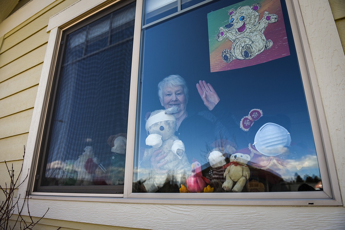 Pat Freebury waves from her front window where she displays a variety of stuffed animals and teddy bears for The Teddy Bear Hunt game on Tuesday, April 21. (Casey Kreider/Daily Inter Lake)