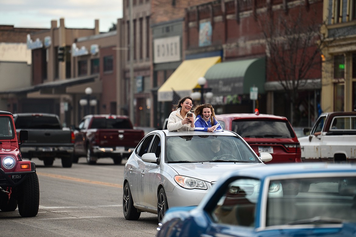 Two girls stick out of the moonroof of a vehicle during the Kruise Kalispell event on Main Street on Friday, April 17. (Casey Kreider/Daily Inter Lake)