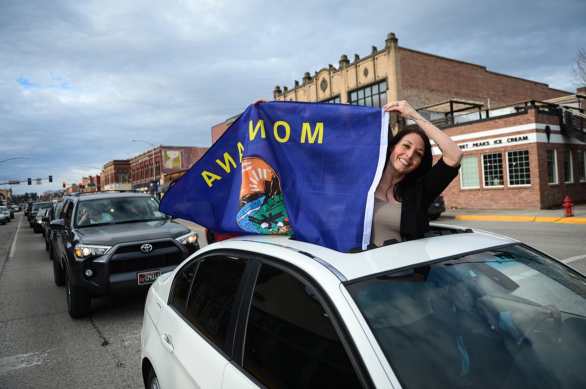 A passenger waves the Montana state flag from a vehicle during the Kruise Kalispell event on Main Street on Friday, April 17. (Casey Kreider/Daily Inter Lake)