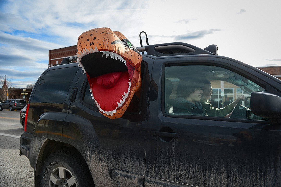 A vehicle with an inflatable Tyrannosaurus rex costume sticking out the window participates in the Kruise Kalispell event on Main Street on Friday, April 17. (Casey Kreider/Daily Inter Lake)