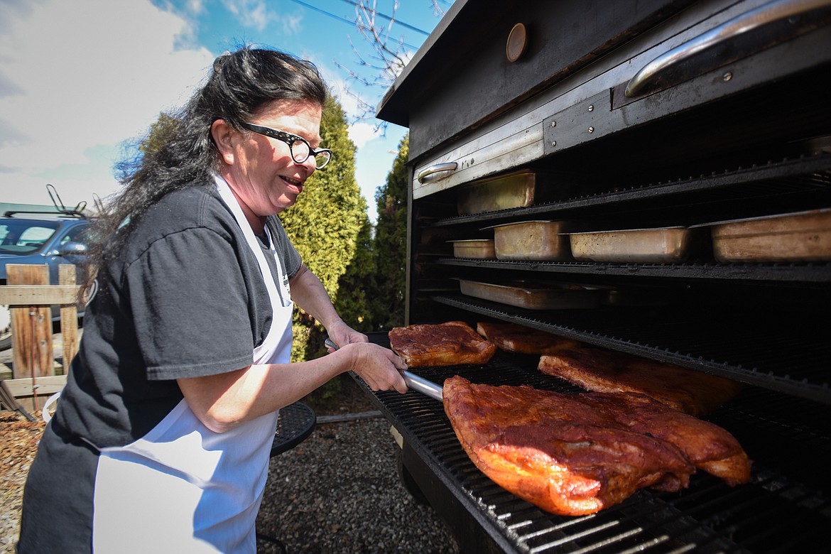 Shawnna Steele, co-owner of The Desoto Grill in Kalispell, tends to some pork bellies cooking on a smoker outside the restaurant on Friday, April 24. (Casey Kreider/Daily Inter Lake)