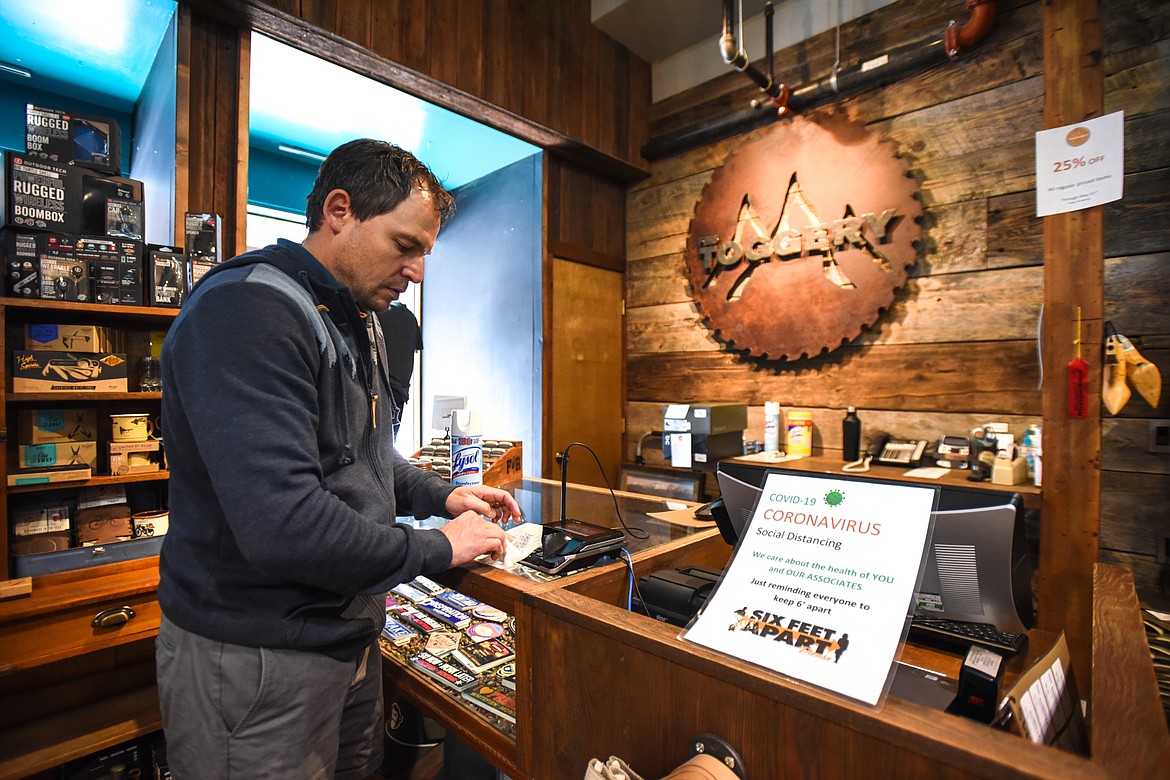 Owner Trek Stephens disinfects a payment terminal at a register at The Toggery in Whitefish on Wednesday, April 29. (Casey Kreider/Daily Inter Lake)