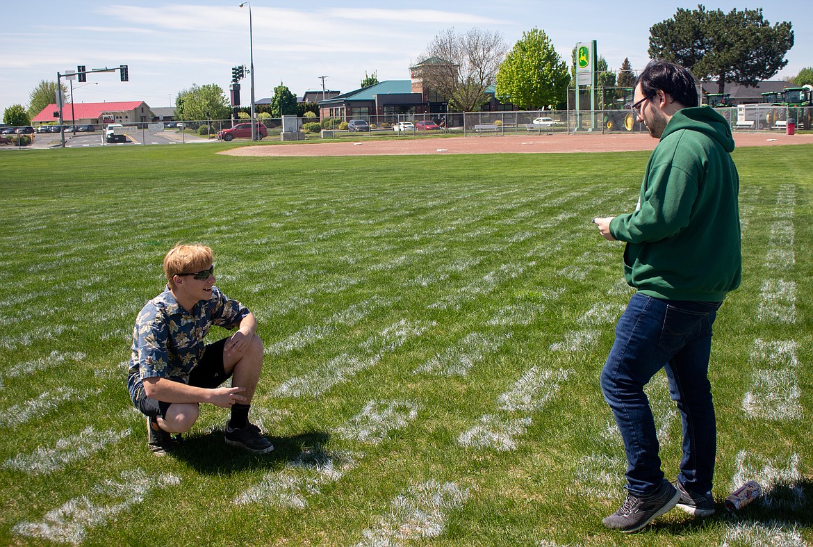 Moses Lake senior Dylan Huber poses by his name on the Field of Chiefs behind Chief Moses Middle School while his friend, Peyton Barret, snaps a photo on Monday afternoon.