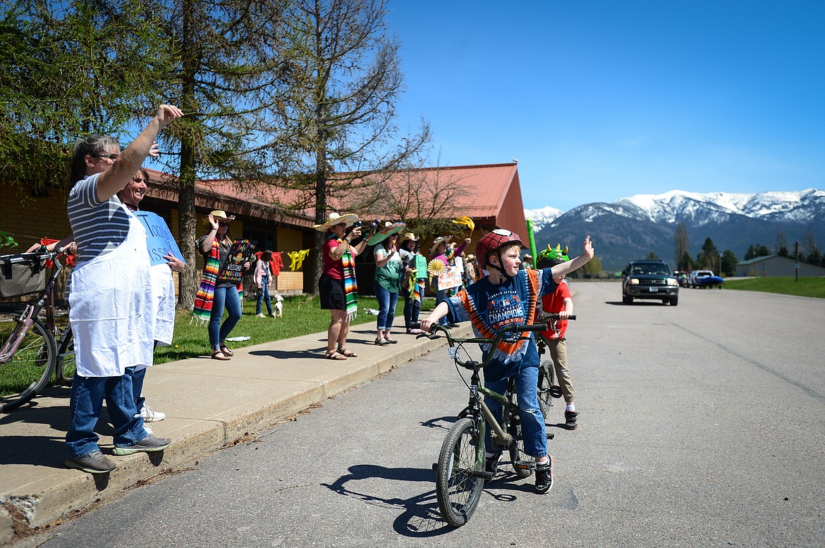 Six-year-old twins Charlie and Ryan Johnston and teachers and staff at Swan River School wave to passing truck drivers as they honk their horn at the Cinco de Mayo Parade outside the school in Bigfork on Tuesday. (Casey Kreider/Daily Inter Lake)