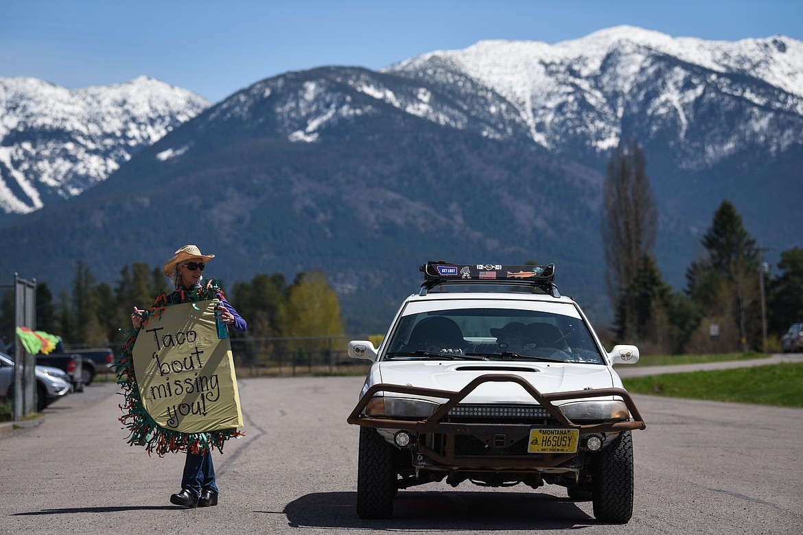 Shelly Emslie, a fifth-grade teacher at Swan River School in Bigfork, holds a sign as she speaks with a parent during a Cinco de Mayo Parade for teachers, students and staff held outside the school on Tuesday. (Casey Kreider/Daily Inter Lake)