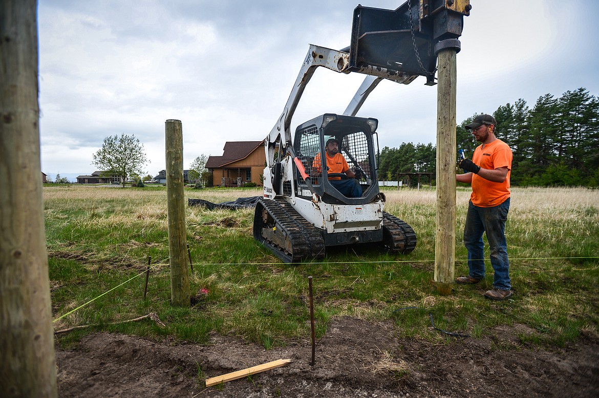 Robert Romero, left, and Jacob Christman drive posts into the ground during an installation near Creston on Wednesday, May 6. (Casey Kreider/Daily Inter Lake)